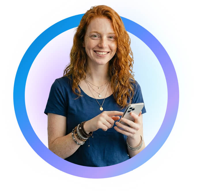 אישה ג'ינג'ית מחייכת ומחזיקה טלפון נייד ביד