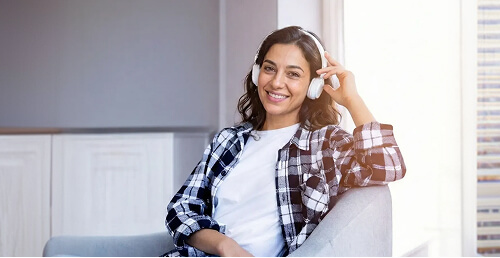 אישה יושבת בבית עם אוזניות במהלך מפגש אונליין